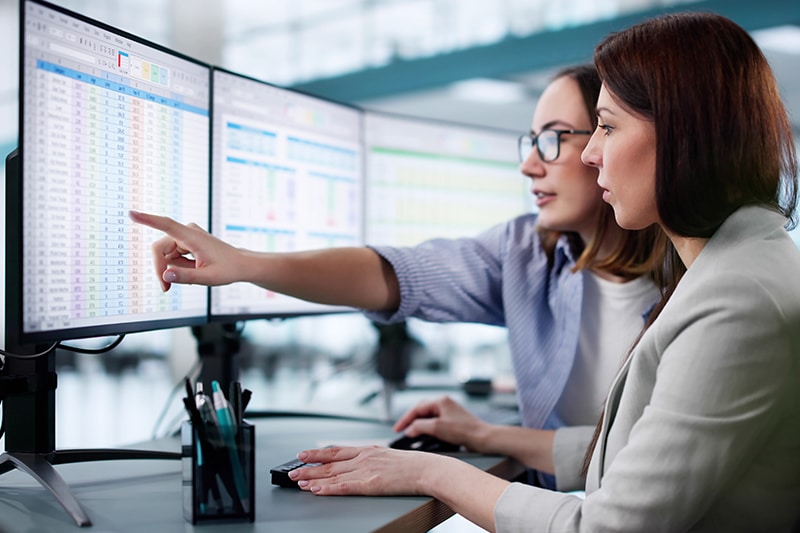 women working on reports on a computer